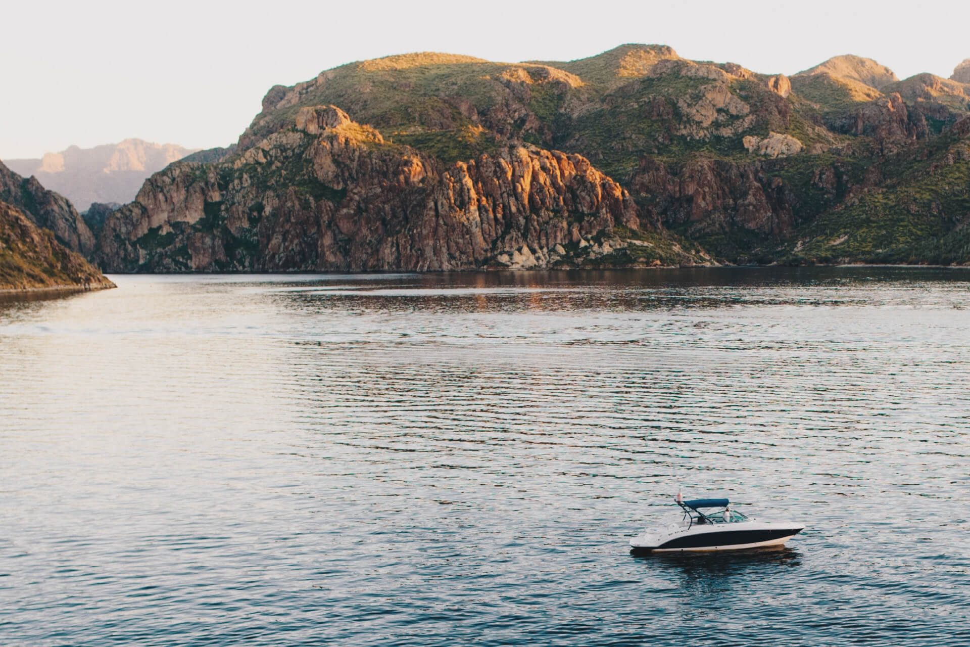 Peaceful boat on Saguaro Lake with desert cliffs